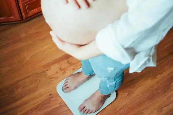 Image of woman weighing herself and experiencing weight gain through pregnancy Smallwood